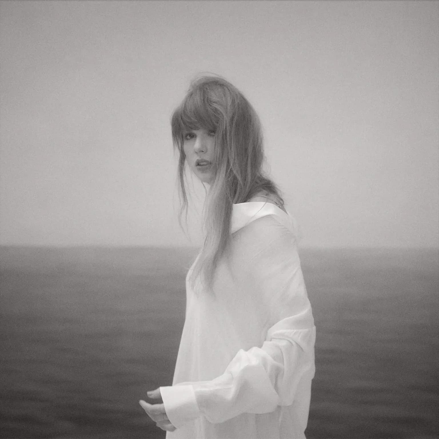 A black-and-white portrait of Taylor Swift in a loose white shirt.